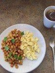 Breakfast potatoes, scrambled eggs and cup of tea on a counter