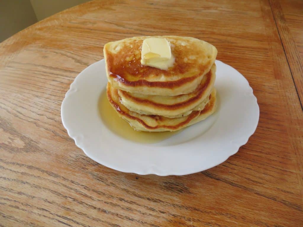 A stack of buttermilk pancakes with butter and syrup