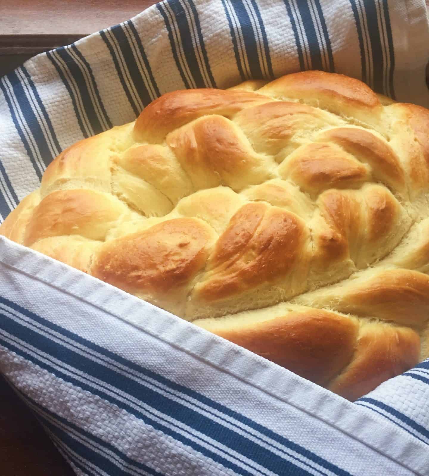 Close up image of challah bread wrapped in a kitchen towel.