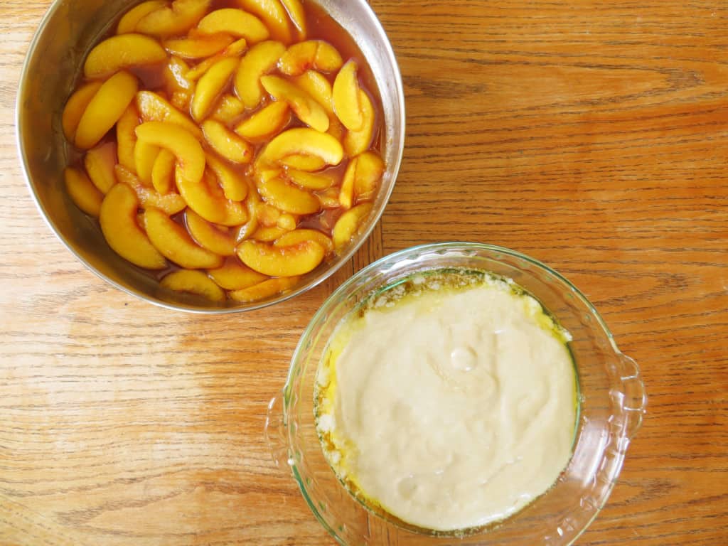 Peach cobbler filling in a skillet and cobbler in a pie pan.