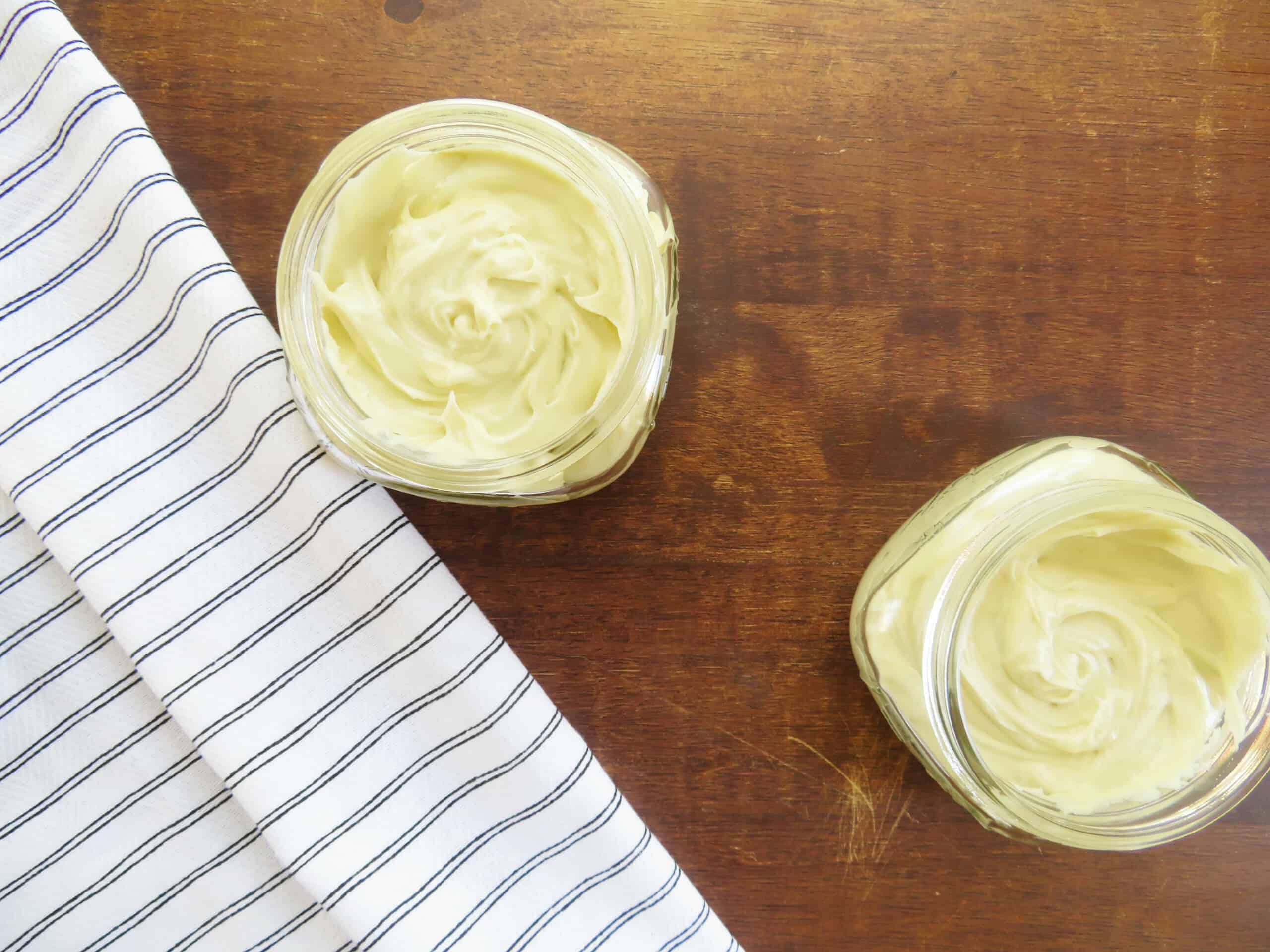 Whipped shea body butter in jars on a table.