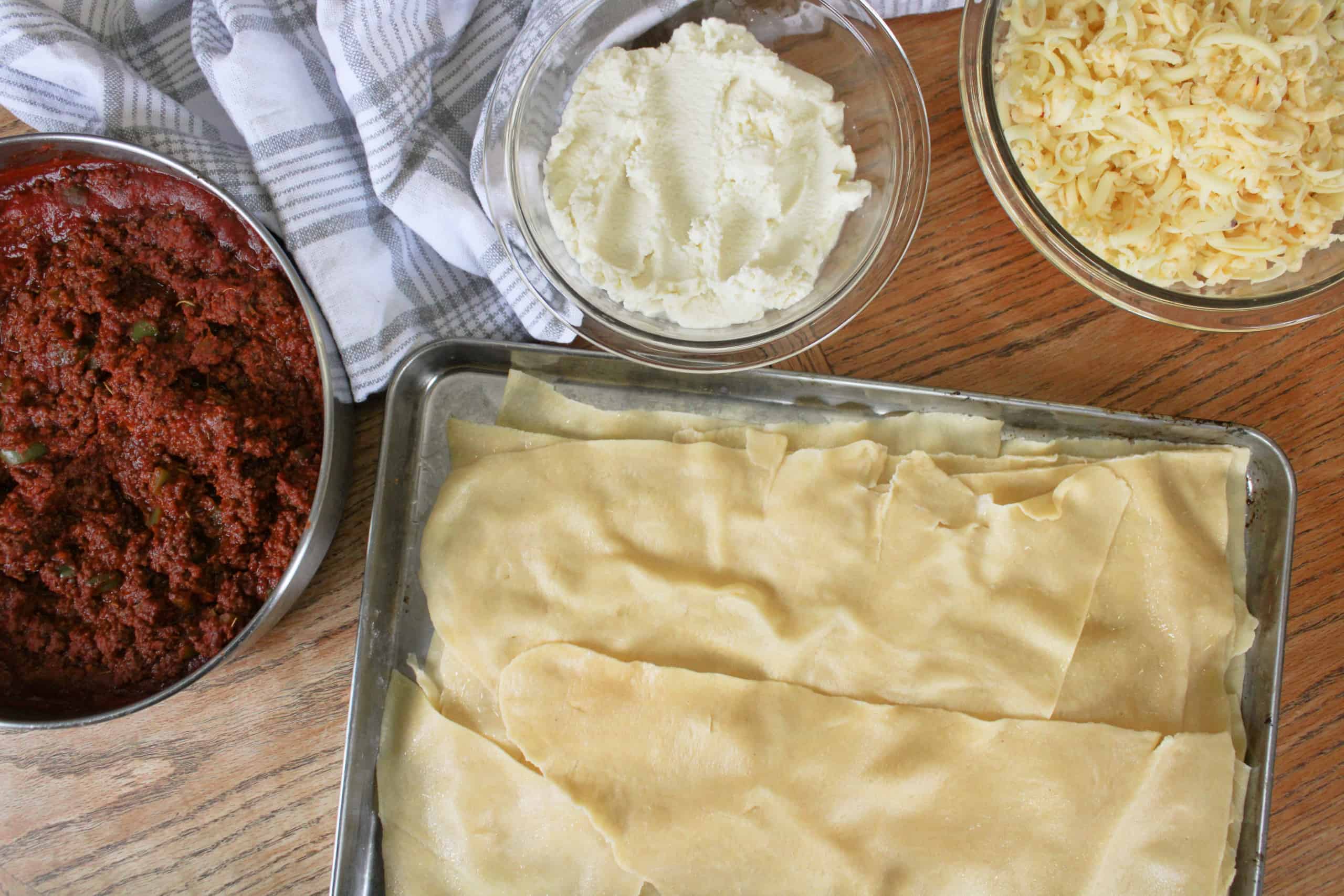 Overhead view of homemade lasagna ingredients on a table.