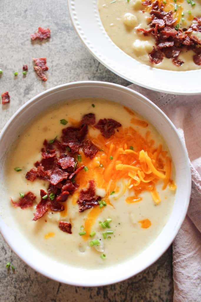 Side view of two bowls of loaded potato soup on a table
