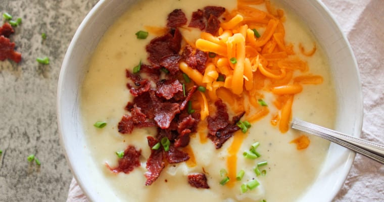 slow cooker loaded baked potato soup in a bowl on a table