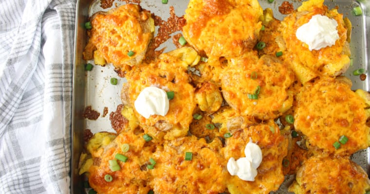 creamy crispy smashed potatoes with sour cream on a sheet pan