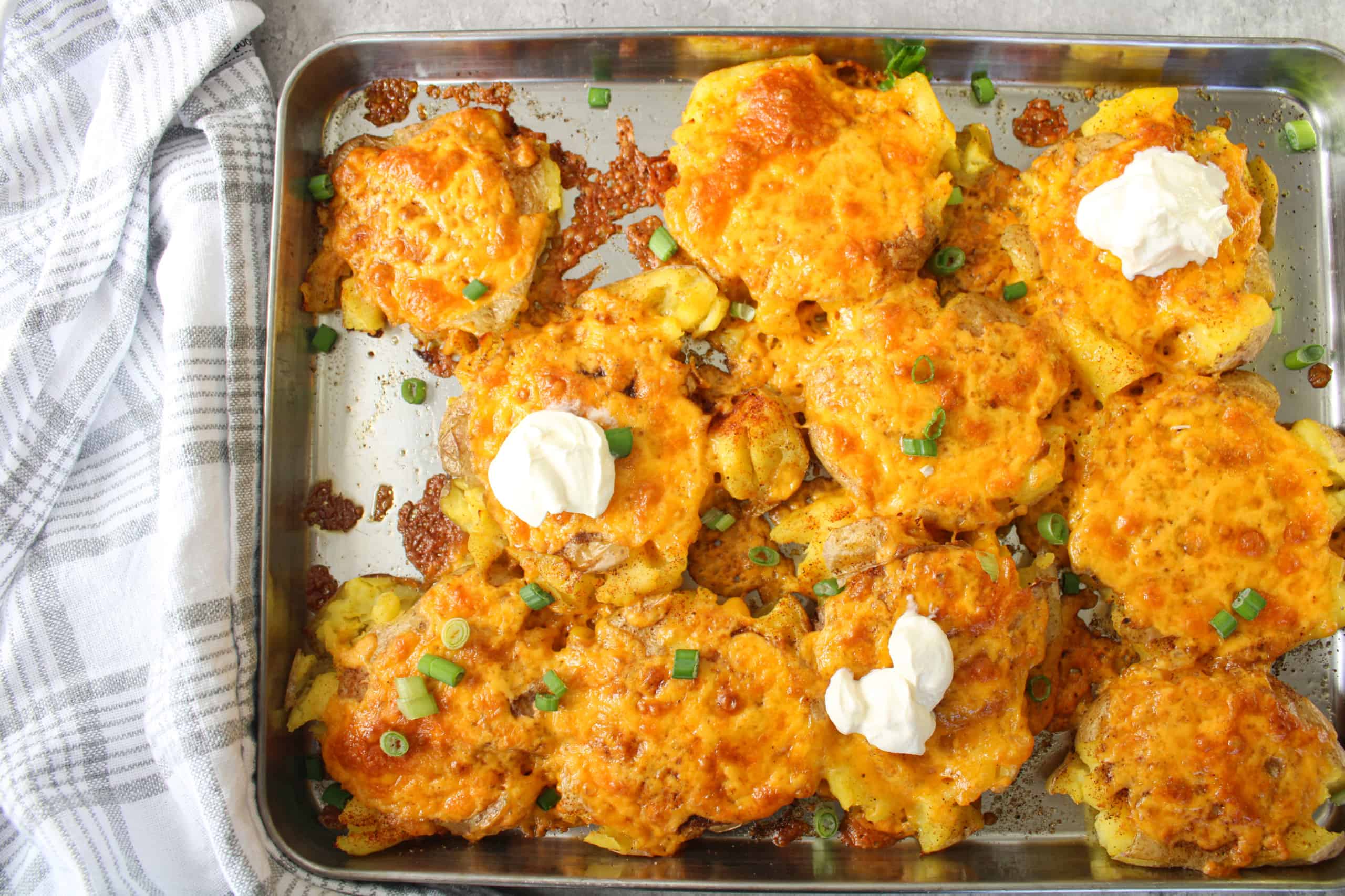 creamy crispy smashed potatoes with sour cream on a sheet pan