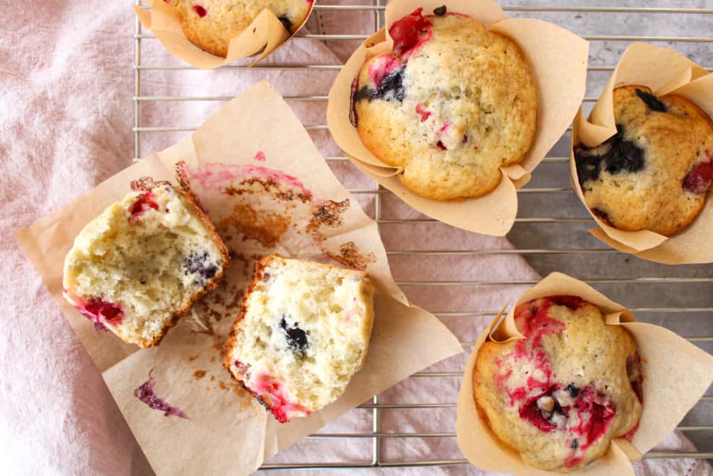 Close up on healthy bakery-style blueberry cranberry muffins on a wire cool.