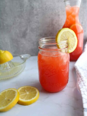Homemade lemonade on a table with lemon slice on the rim.