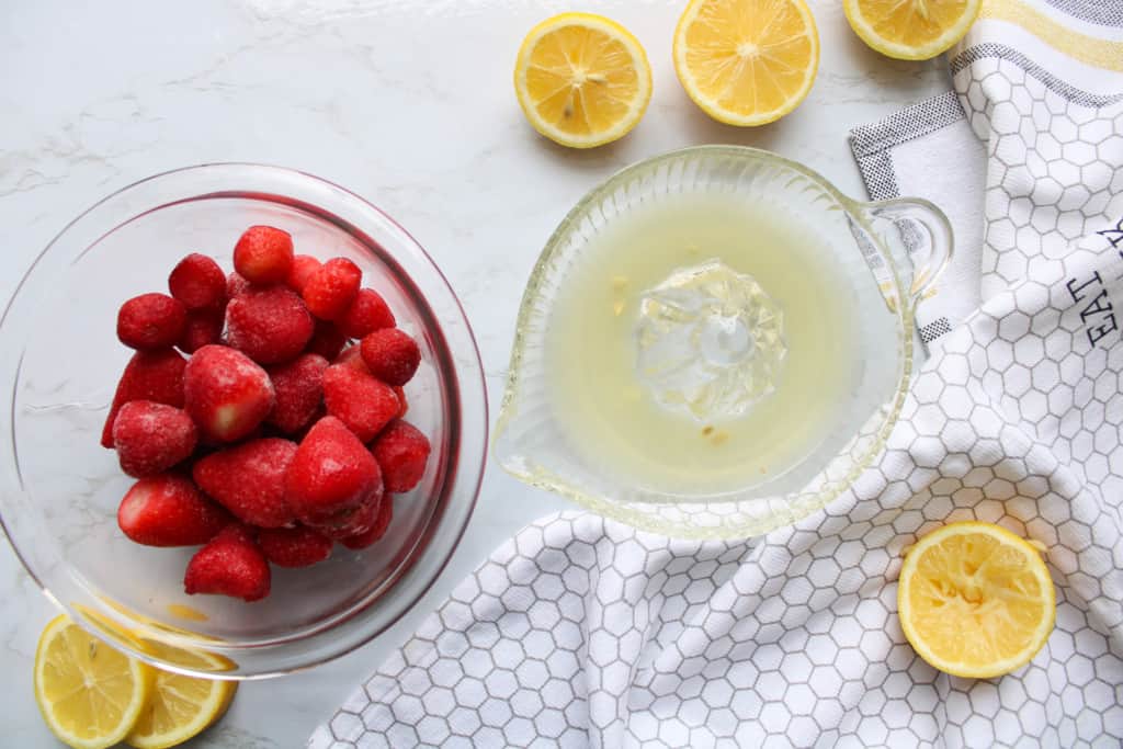 top view of frozen strawberries and squeezed lemons on a table
