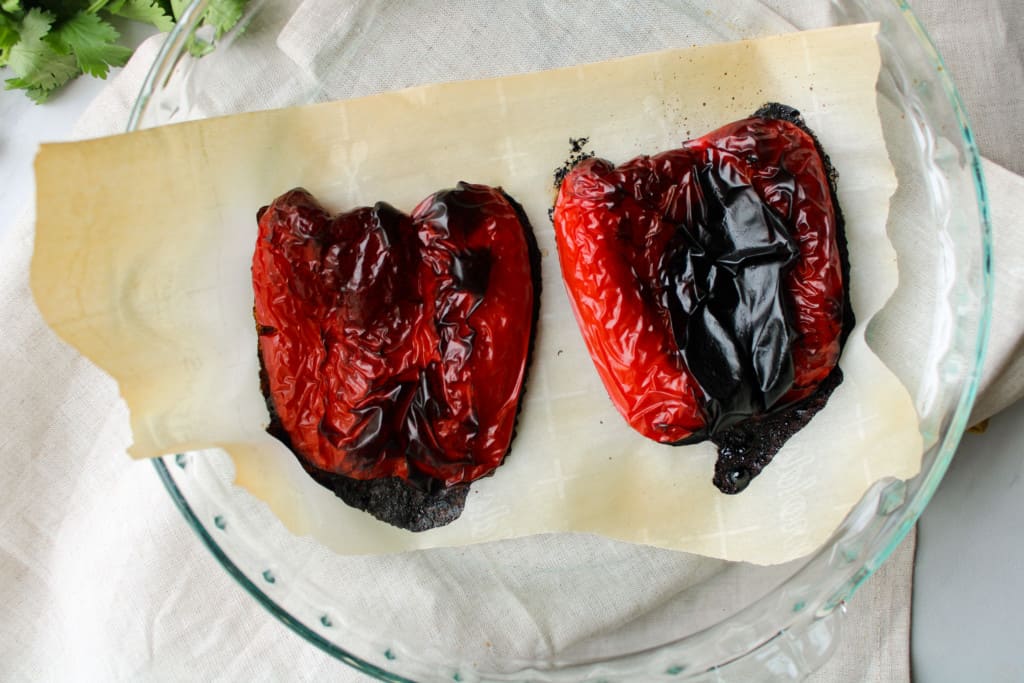 Close up on homemade roasted red bell peppers in a baking dish.