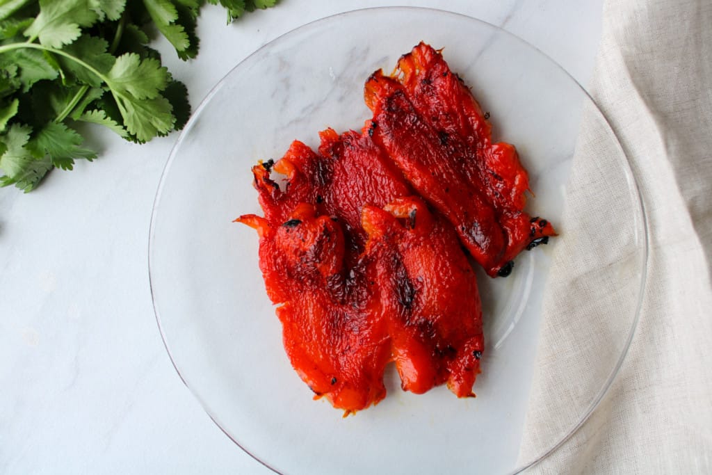 Roasted peppers on a plate with the charred skin removed.