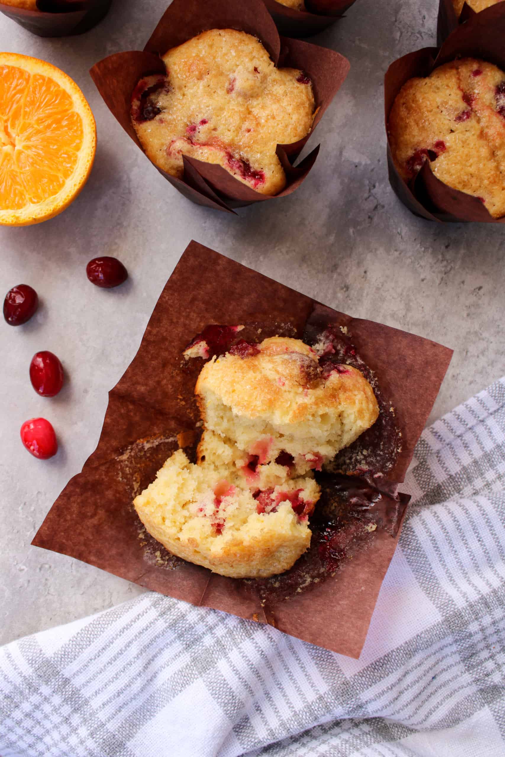 Orange cranberry muffin sliced in half on a table.