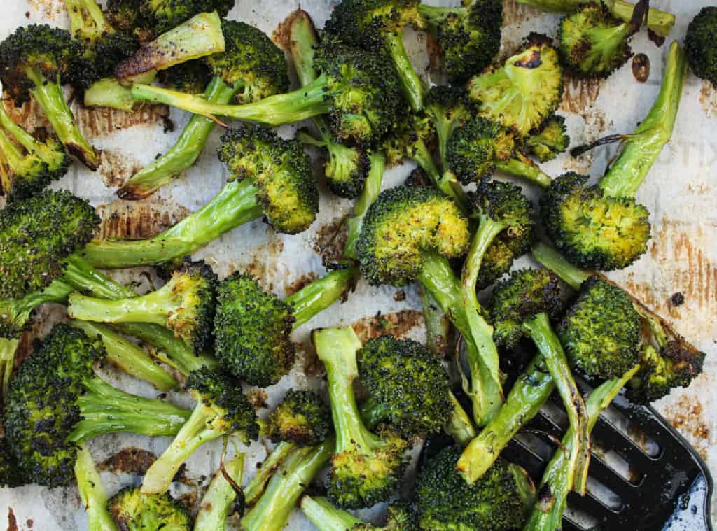 Top view of easy roasted broccoli on a sheet pan with spatula. 