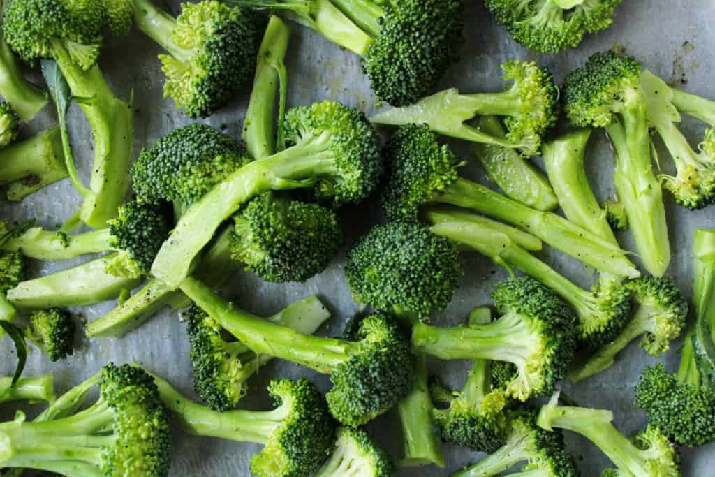 Top view of uncooked broccoli florets in a sheet pan.