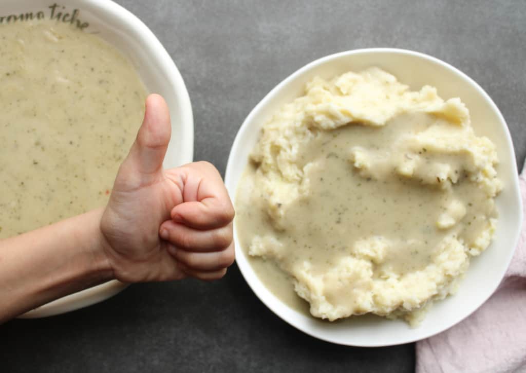Child's hand with mashed potatoes and homemade gravy. 