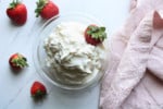 Homemade whipped cream in a bowl with fresh strawberries.