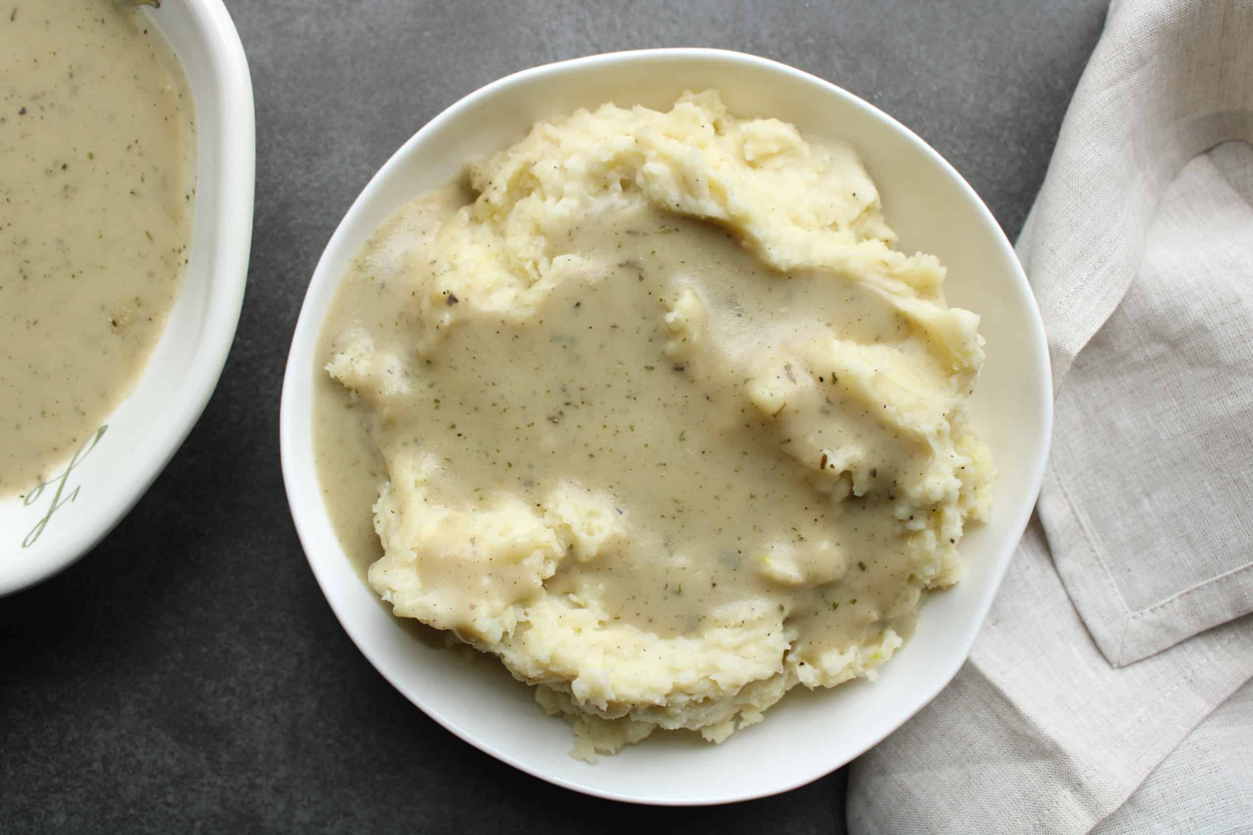 Homemade gravy over mashed potatoes in a bowl on the table.
