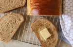 Close up of a slice of honey whole bread with butter and honey on a wire rack.