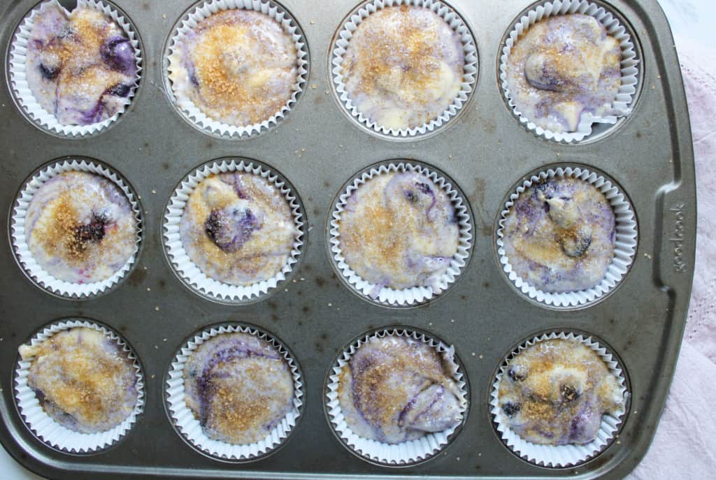 Muffins batter in muffin pan with sugar on top. 