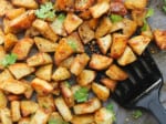 Close up on crispy za'atar seasoned potatoes in a baking pan with a spatula.