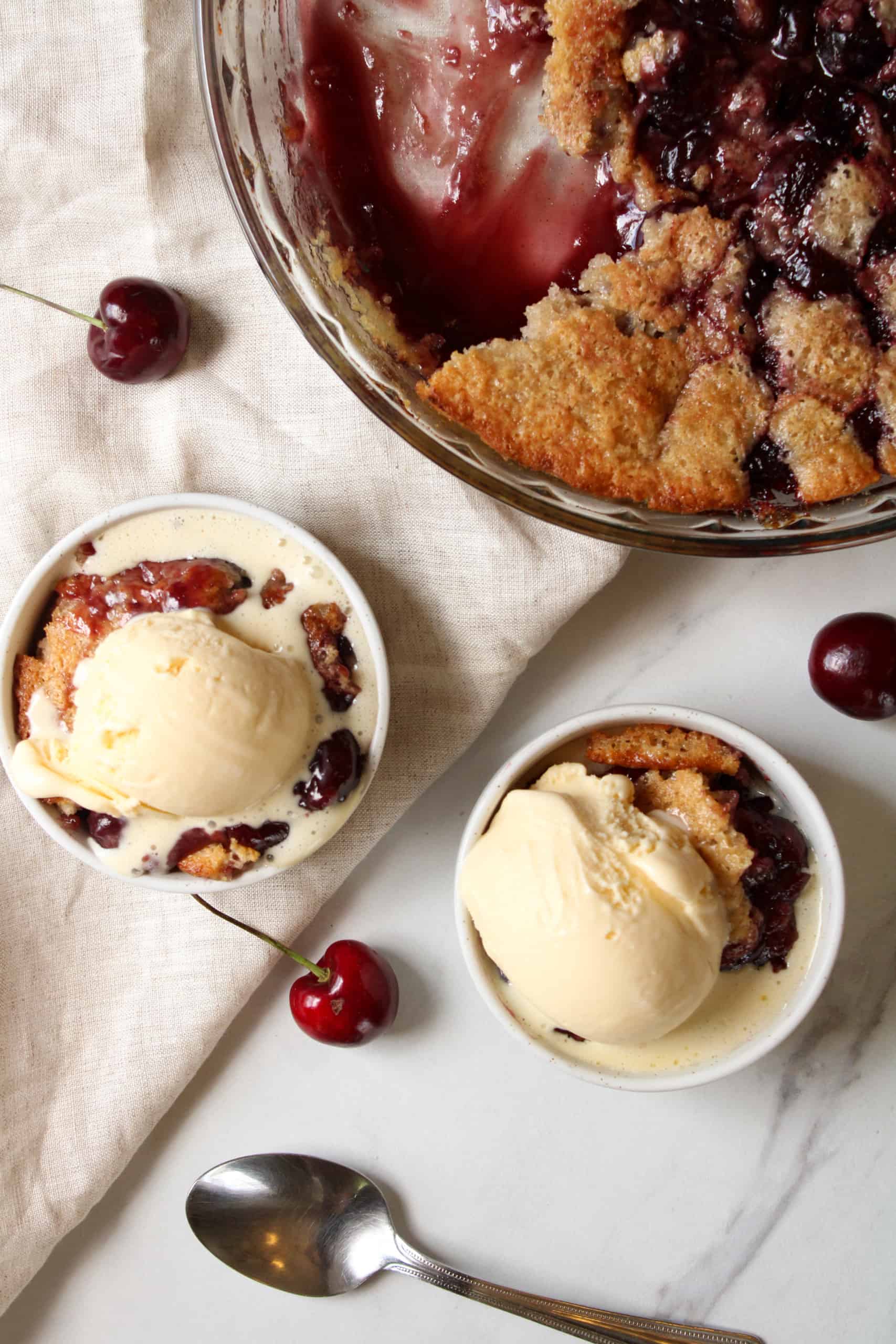 Cherry fruit cobbler with scoop of vanilla ice cream on top.