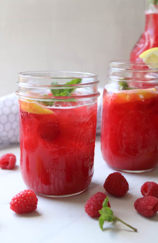 Close up on two glasses of raspberry lemonade on a table. 