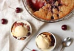 Overhead of sweet fruit cobbler in bowls with ice cream on top.