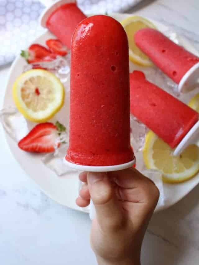 Boy holding strawberry popsicle.