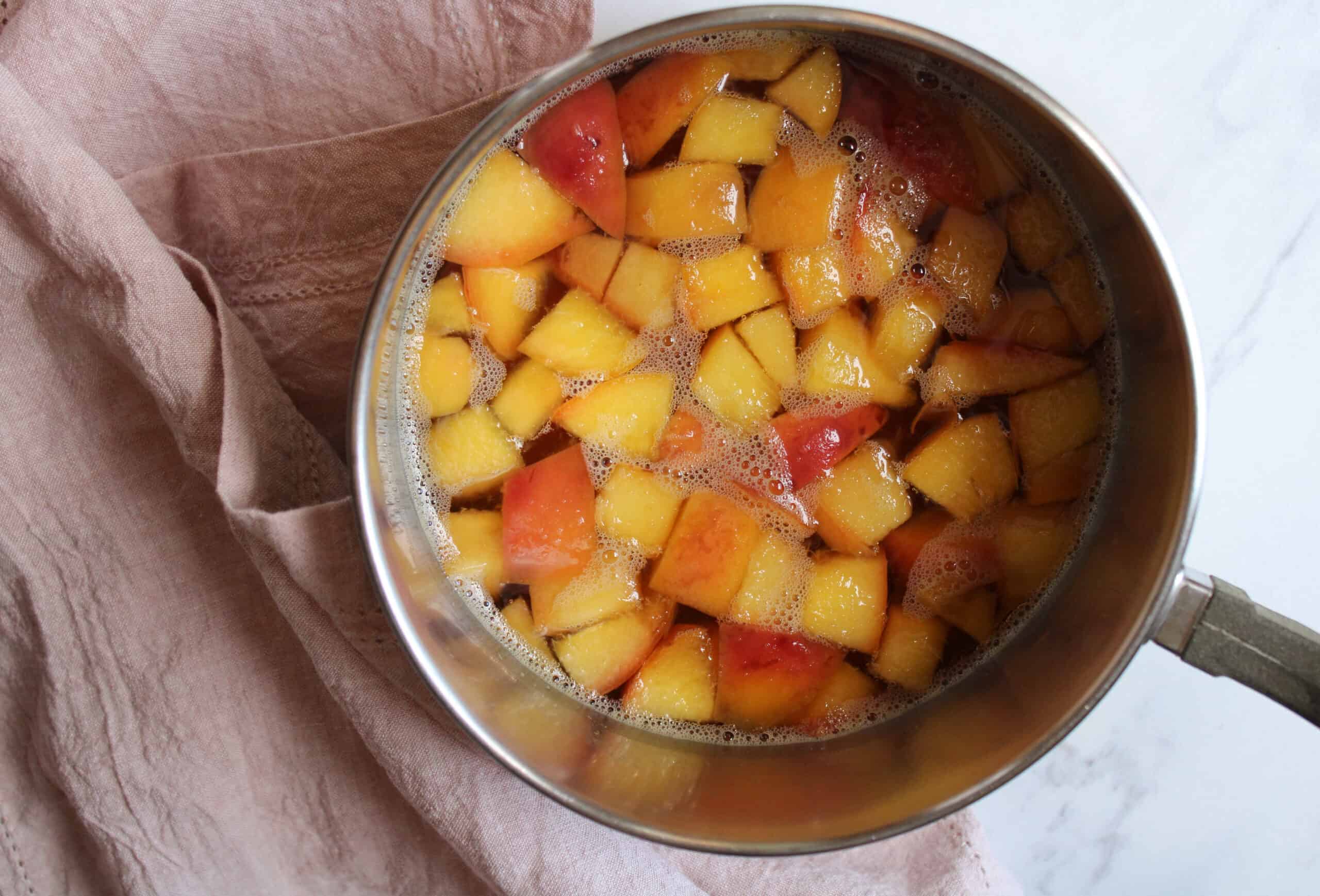 Peaches cut into cubes in a pot with a sugar syrup.