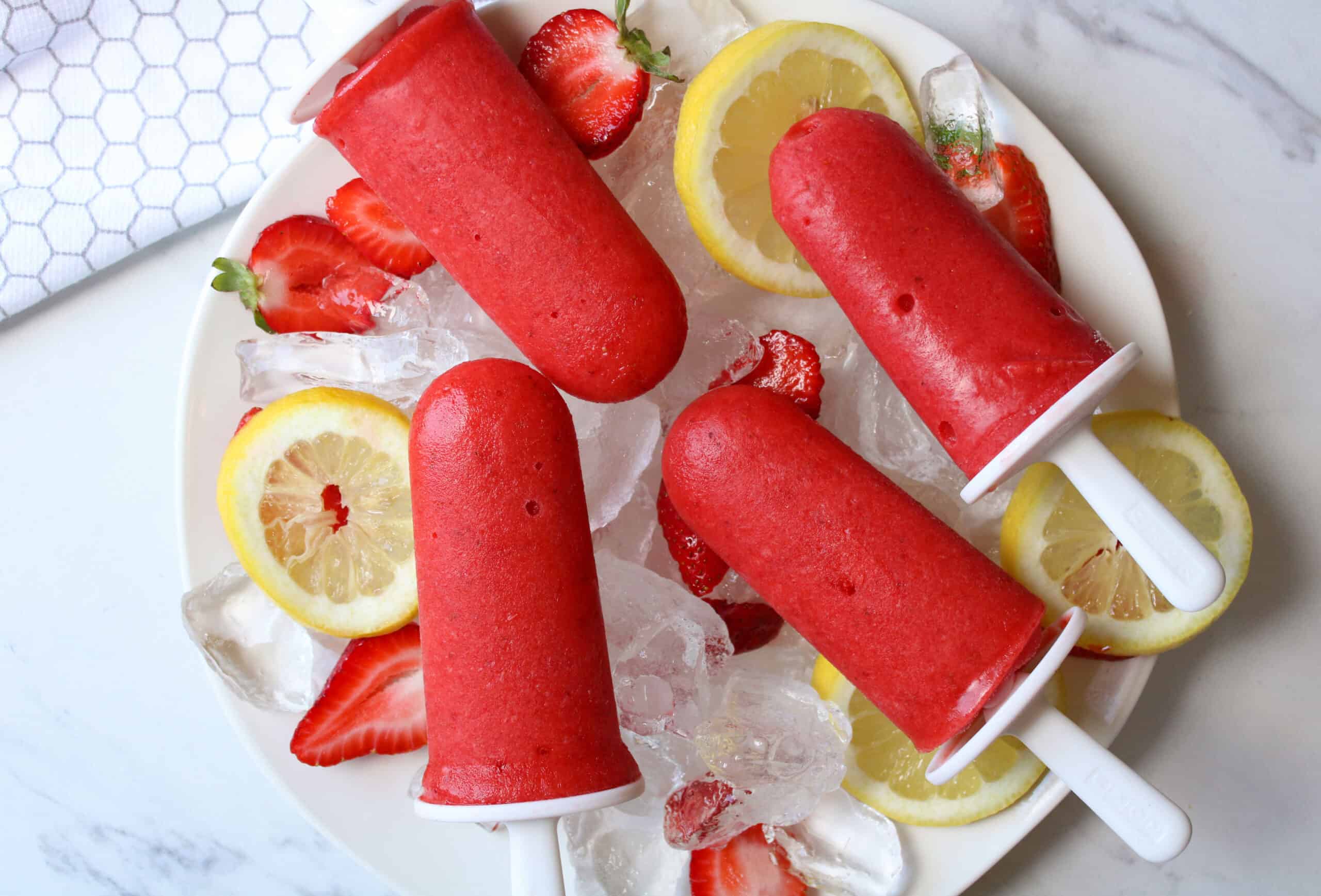 Plate of 3 ingredient homemade strawberry lemonade popsicles.