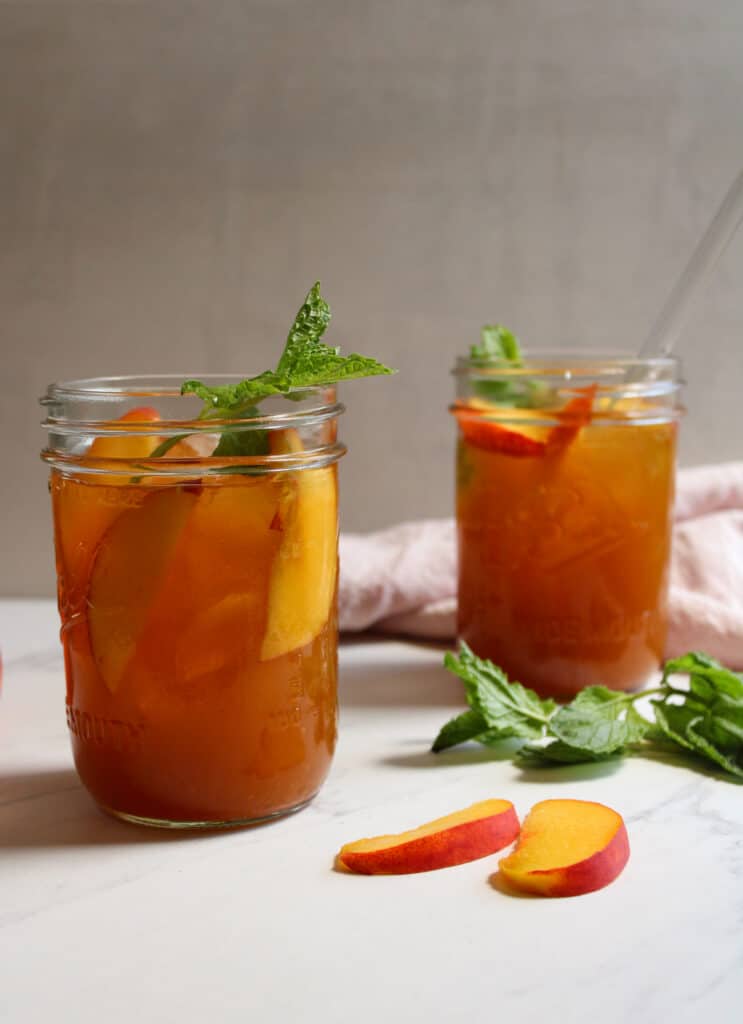 Two glasses of iced sweet tea with peaches. 