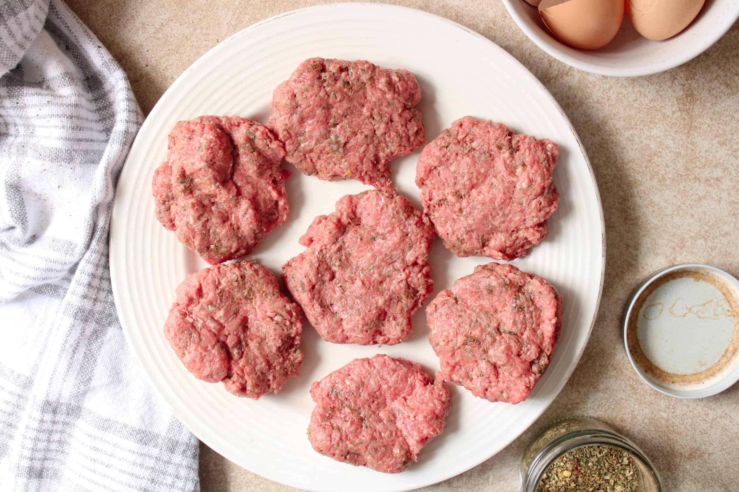Raw ground beef patties on a plate.