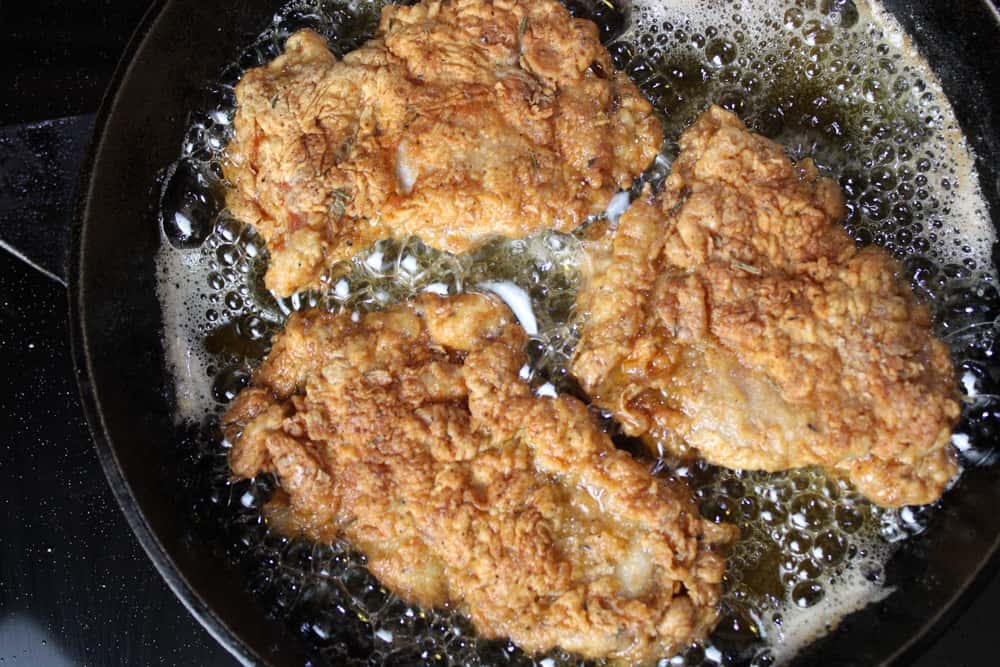 Chicken frying in a cast iron skillet.