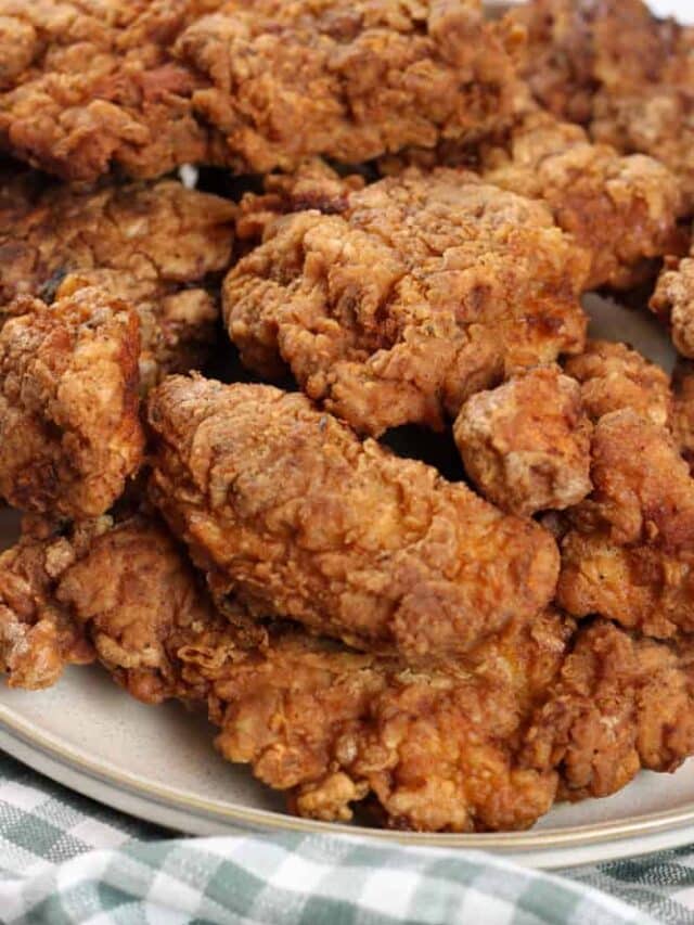 A close up on a pan fried chicken on a plate.