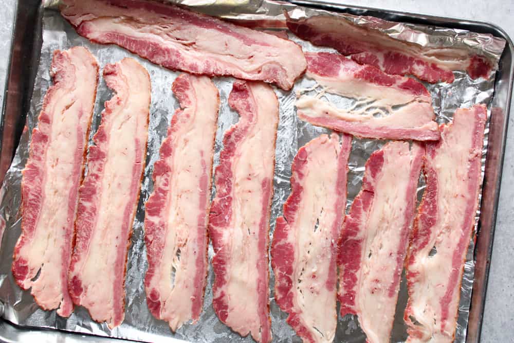 Raw bacon on a sheet pan. 