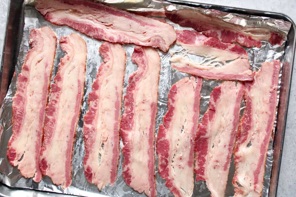 Raw bacon on a sheet pan.