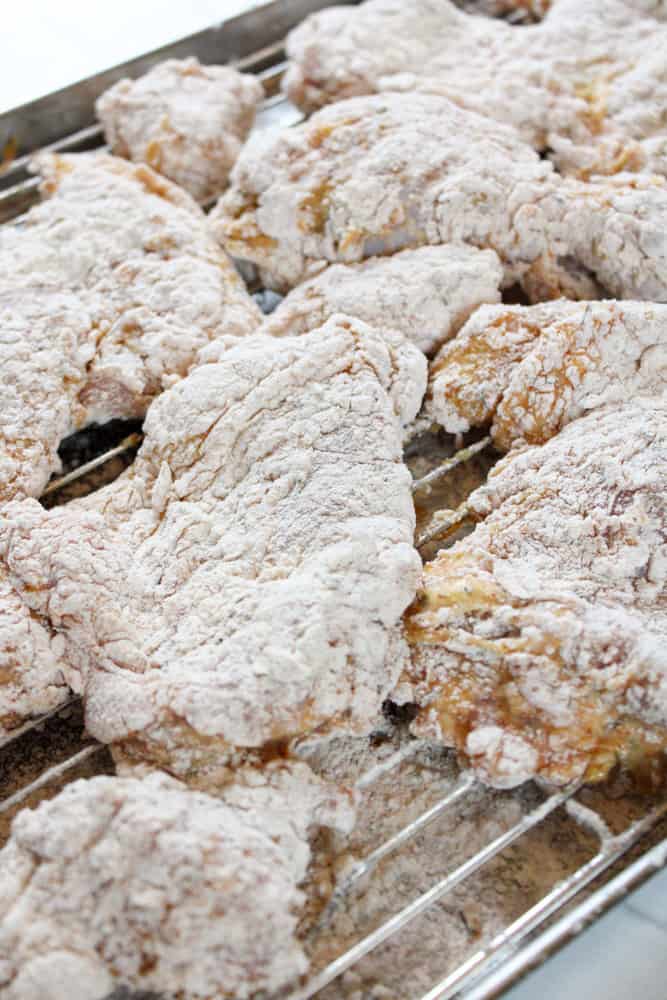 Close up on dredged chicken on a wire rack.