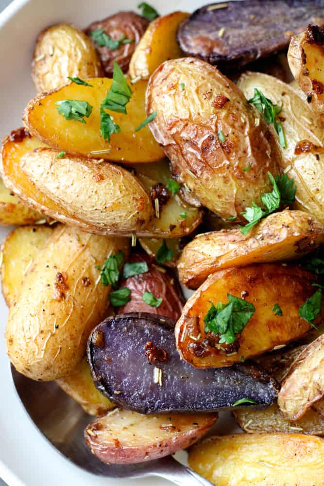 Close up on roasted potatoes with fresh herbs.