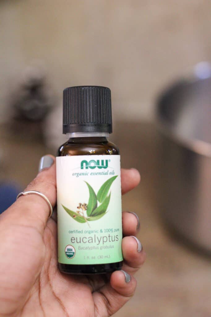 Woman holding eucalyptus essential oil bottle.