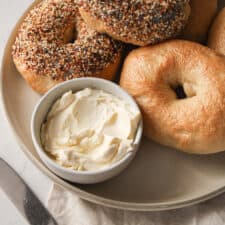 Everything bagels on a plate with cream cheese.