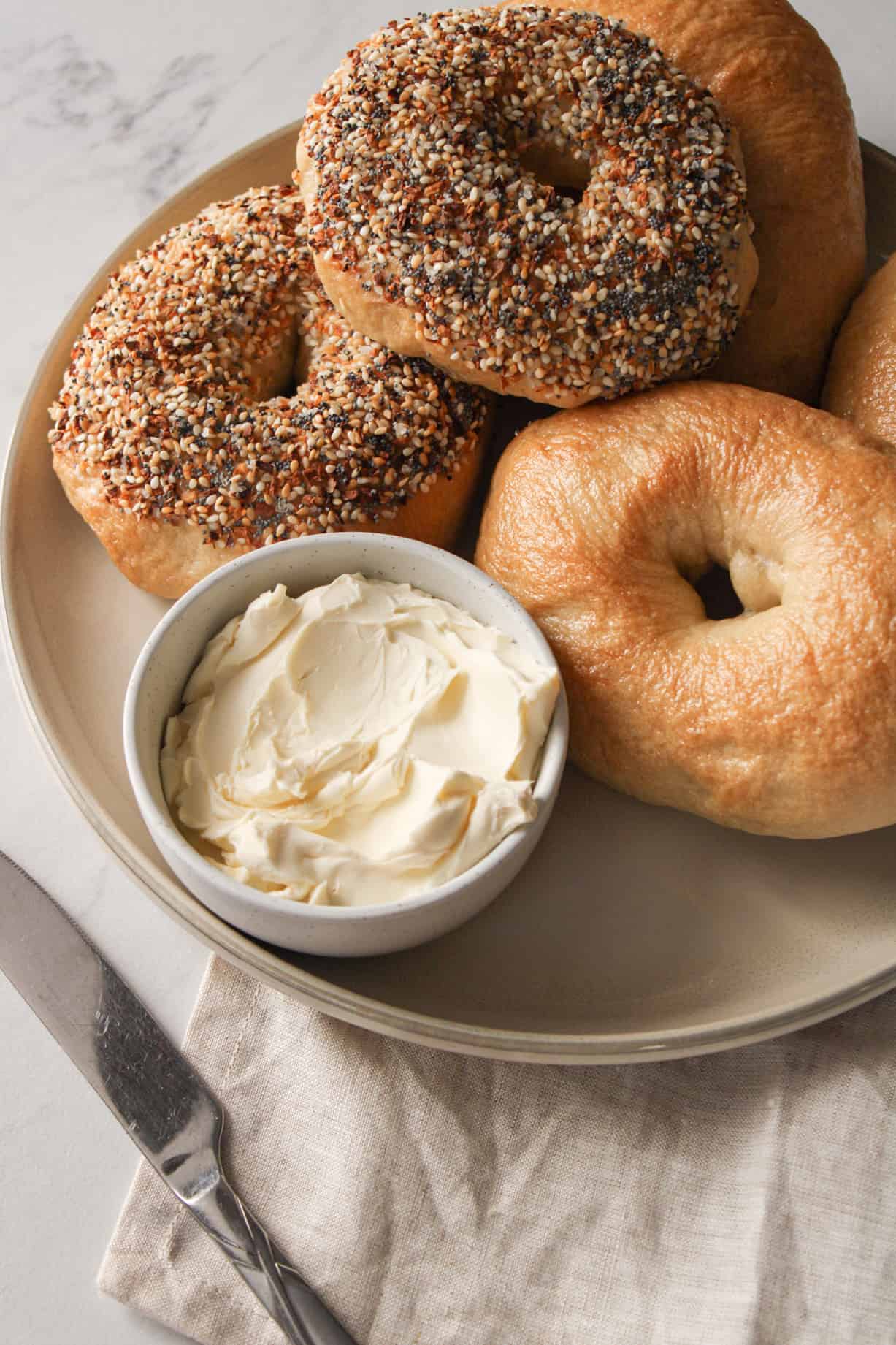 Everything bagels on a plate with cream cheese.