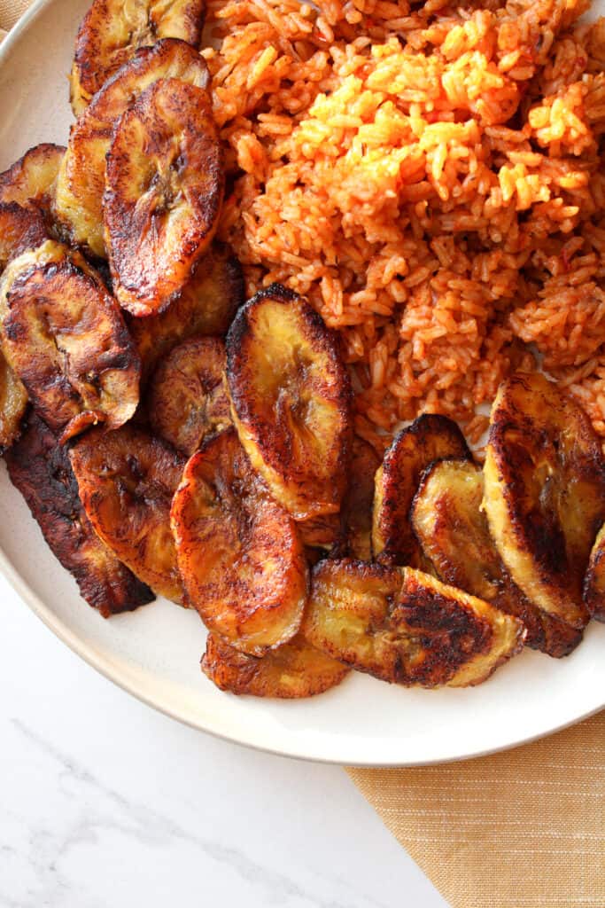 African plantains snack on a plate with jollof rice. 