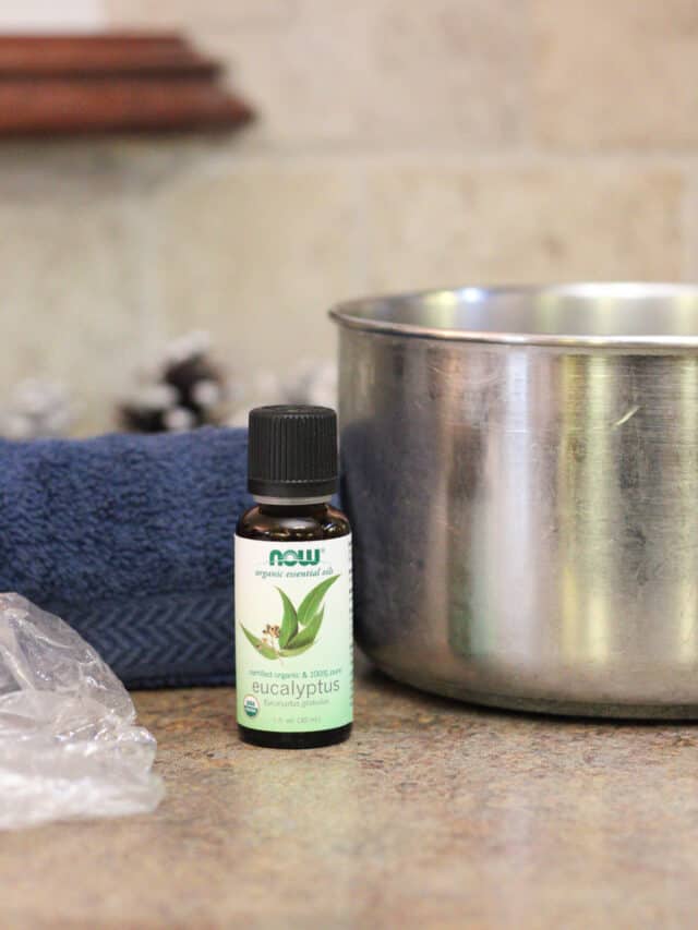Side view of essential oil bottle with towel and pot on a table.