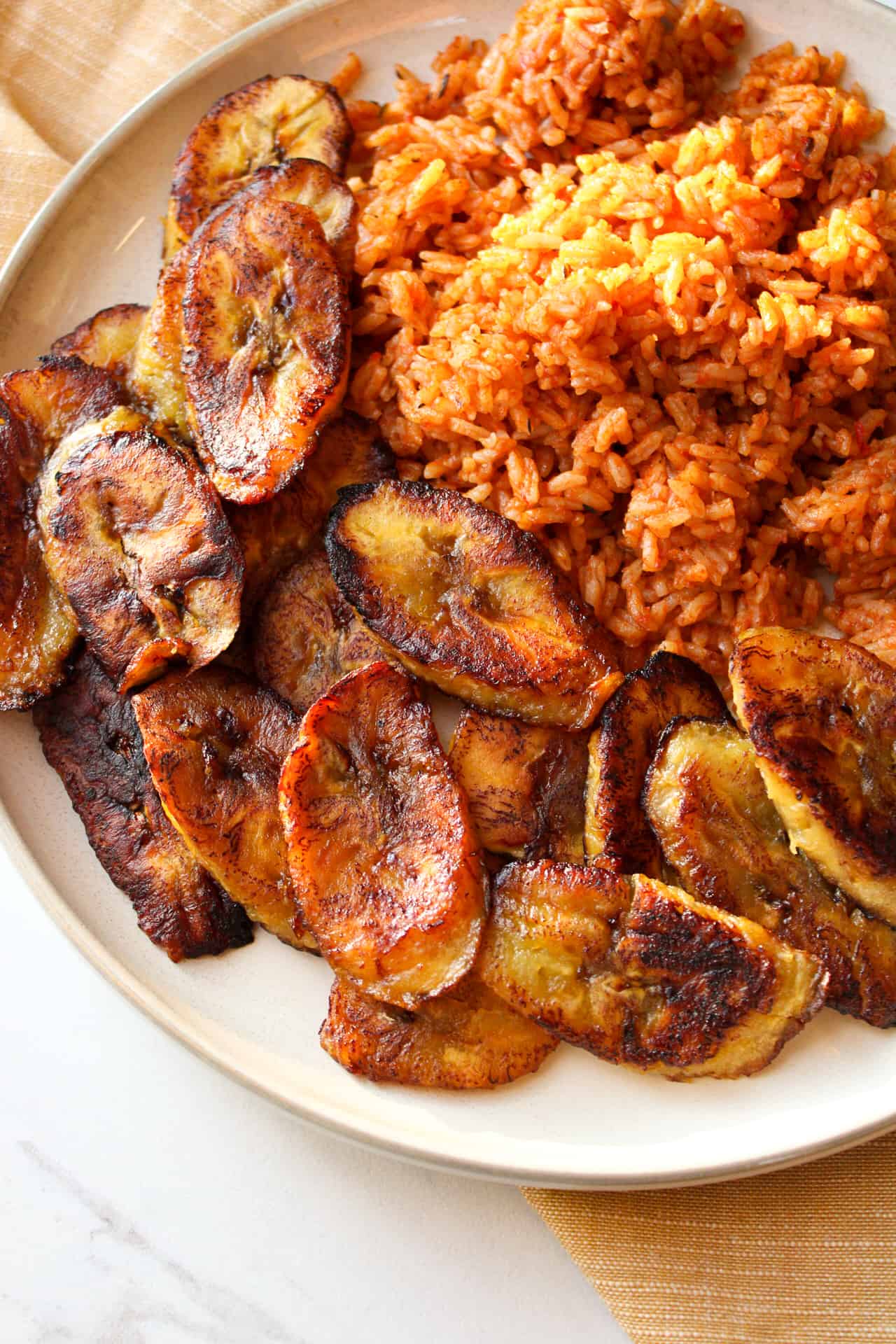 Fried plantains with Jollof rice on plate.