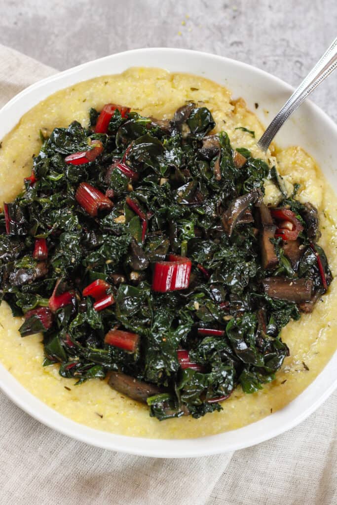 Top view of creamy polenta with greens in a bowl.