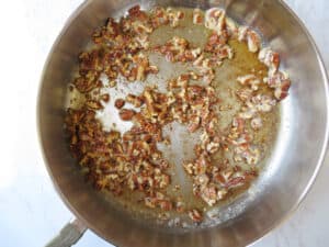 Butter pecans in a skillet.