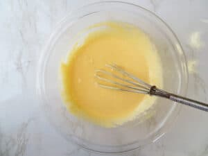 Eggs creamed with sugar in a bowl with a whisk.