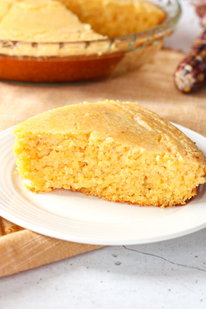 Side view of a slice of cornbread on a plate.