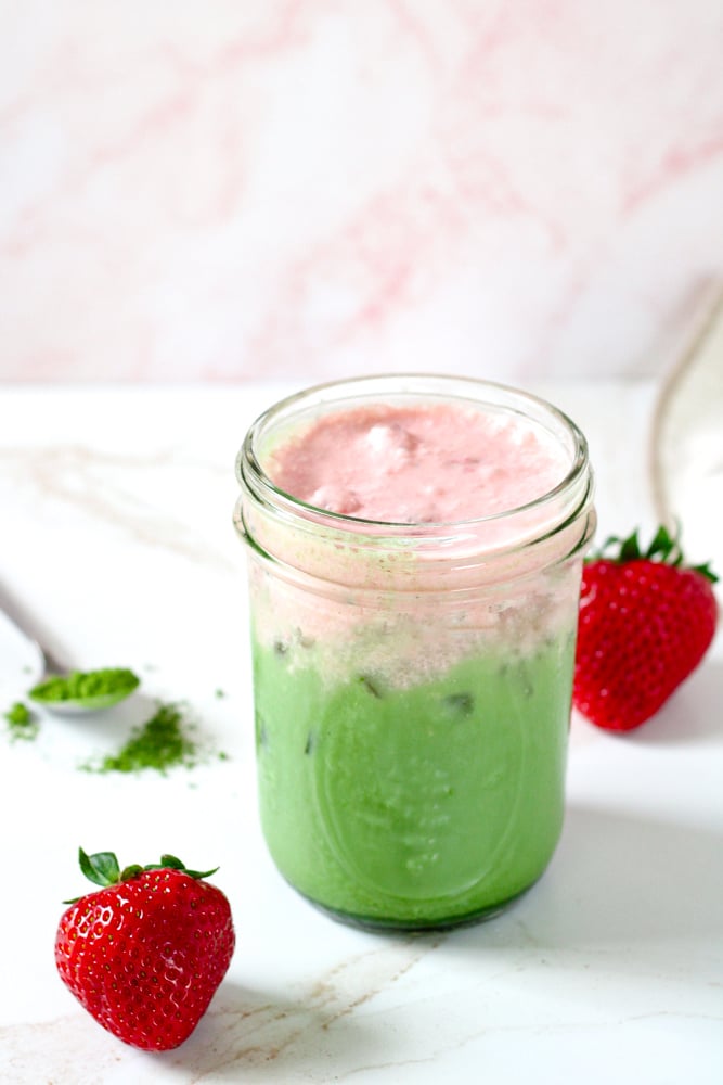 Side image of matcha latte with strawberry cream on top in a mason jar.
