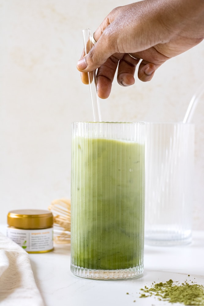 Woman's hand stirring iced matcha.